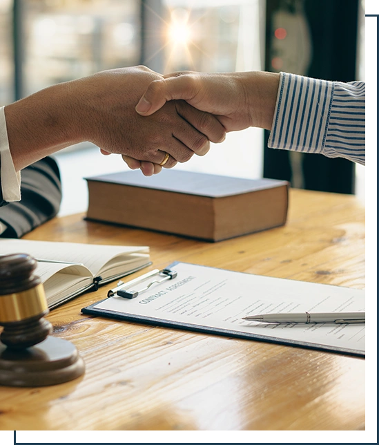Close-up view of a lawyer holding a client's hand, making an agreement, signing a contract, a side judge's hammer and brass scales