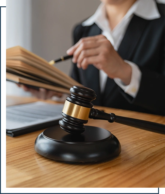 Asian female lawyer or legal advisor working on the scale of justice sitting at her desk and holding a pen to look at the information Detailed content about the scale of jurisprudence to study.